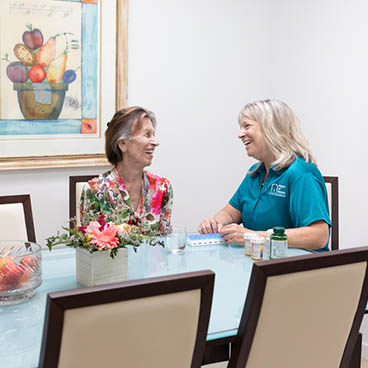 A female Right at Home caregiver is helping her senior female client with her medication