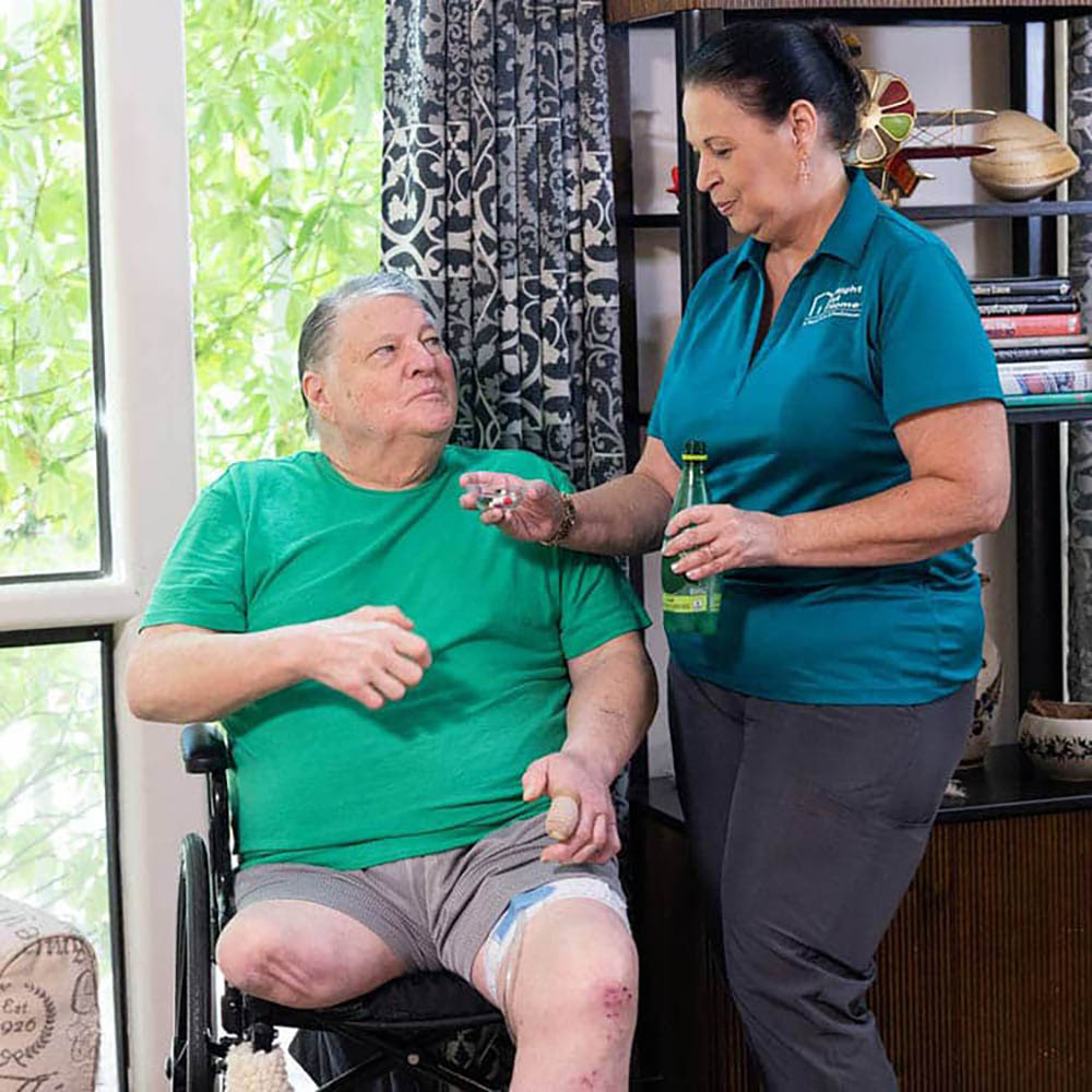 A female caregiver showing a bottle of pills to a female patient. A female caregiver showing a bottle of pills to a female patient.