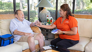 A female Right at Home caregiver is helping her senior male client with his medication