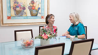 A female Right at Home caregiver is helping her senior female client with her medication